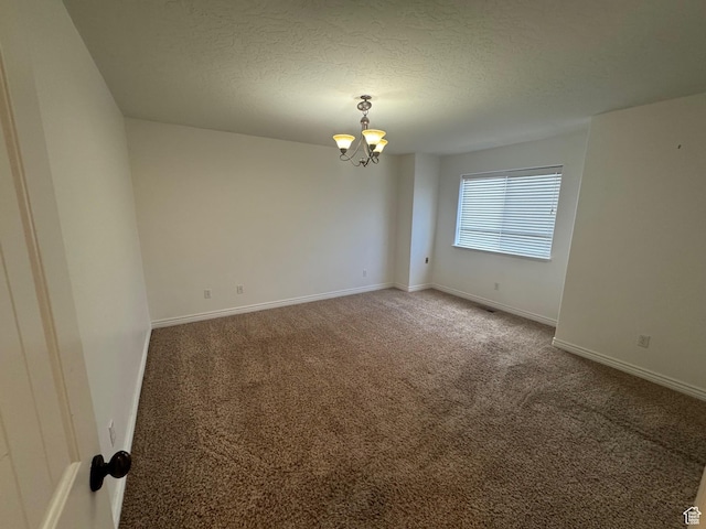 unfurnished room with a chandelier, a textured ceiling, carpet flooring, and baseboards