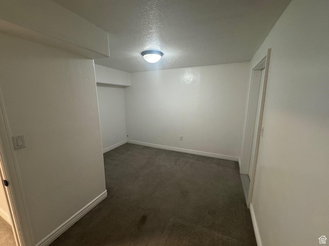 finished below grade area with a textured ceiling, carpet flooring, and baseboards