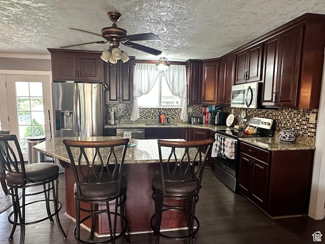 371 S Willard Peak Rd S, Mantua, UT 84324 - kitchen with dark wood-style floors, appliances with stainless steel finishes, tasteful backsplash, and a breakfast bar