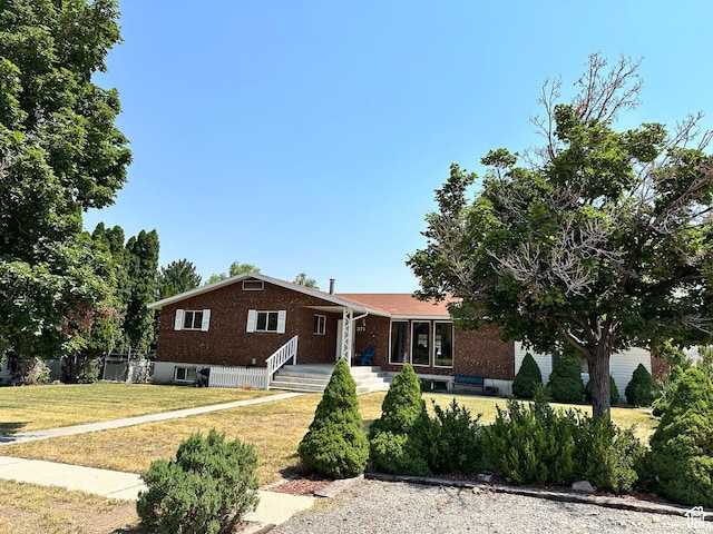 view of front of house with a front lawn, fence, and brick siding