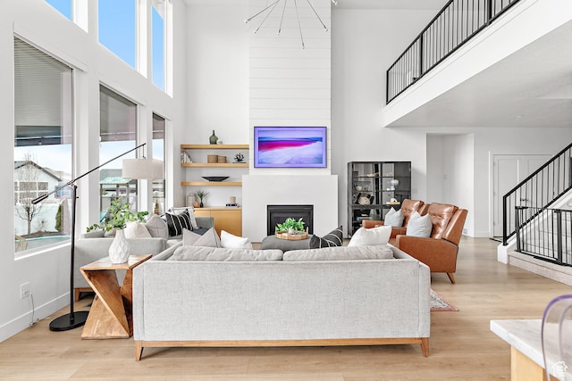 1228 E 1030 N, American Fork, UT 84003 - living area with baseboards, a glass covered fireplace, a towering ceiling, stairs, and light wood-type flooring