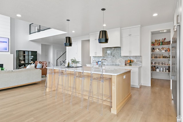 1228 E 1030 N, American Fork, UT 84003 - kitchen featuring a center island with sink, a breakfast bar area, light wood-style floors, white cabinetry, and backsplash