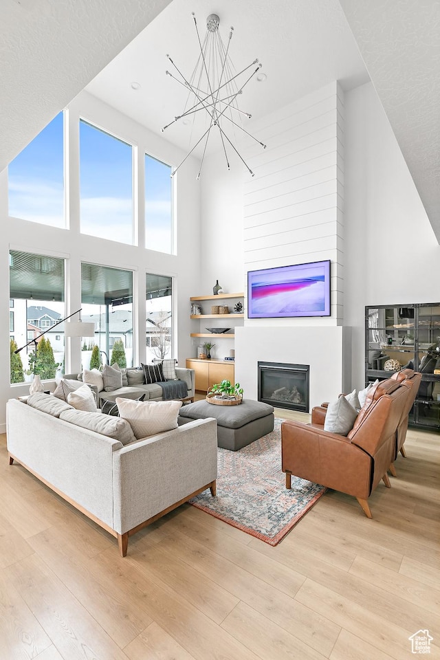 1228 E 1030 N, American Fork, UT 84003 - living area featuring light wood-type flooring, a high ceiling, a notable chandelier, and a glass covered fireplace