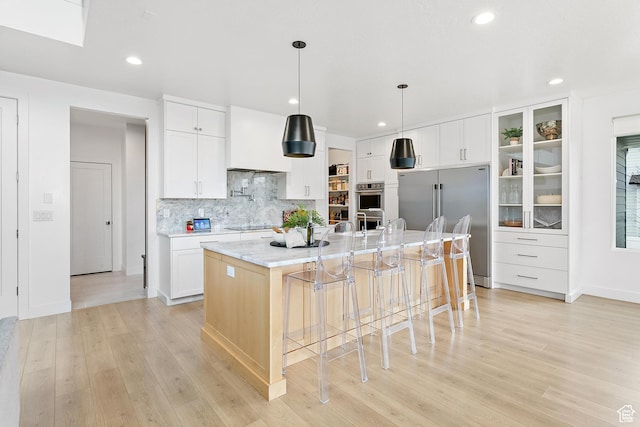 1228 E 1030 N, American Fork, UT 84003 - kitchen with appliances with stainless steel finishes, wall chimney exhaust hood, light wood finished floors, and a kitchen bar