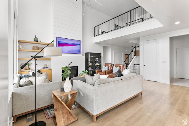 1228 E 1030 N, American Fork, UT 84003 - living room featuring recessed lighting, wood finished floors, a towering ceiling, stairway, and a glass covered fireplace