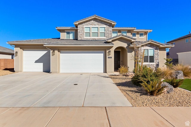 view of front of house featuring driveway, stone siding, a garage, and stucco siding