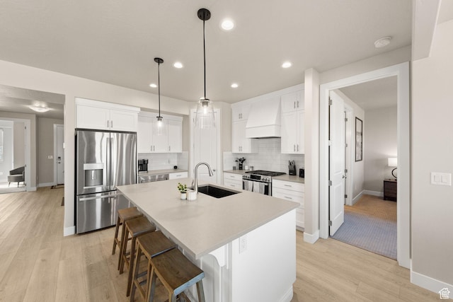 4712 W 2820 S, Hurricane, UT 84737 - kitchen featuring stainless steel appliances, premium range hood, a sink, light wood-style floors, and a kitchen island with sink