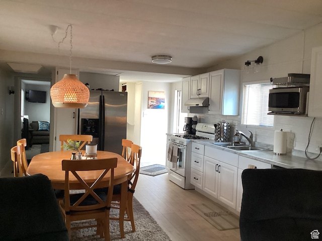 255 N 1st St E, Manila, UT 84046 - kitchen with light wood-style flooring, stainless steel appliances, under cabinet range hood, backsplash, and a sink