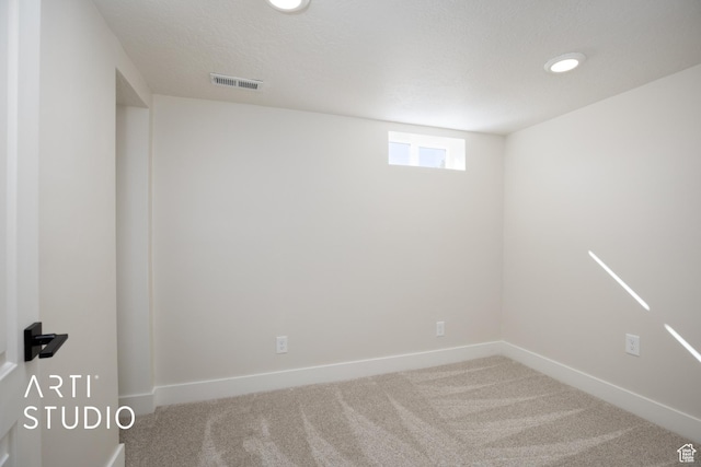 below grade area featuring a textured ceiling, recessed lighting, visible vents, baseboards, and carpet