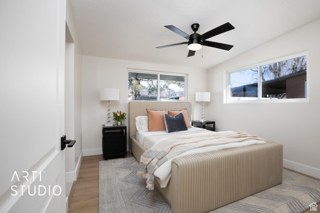 bedroom with ceiling fan, wood finished floors, and baseboards