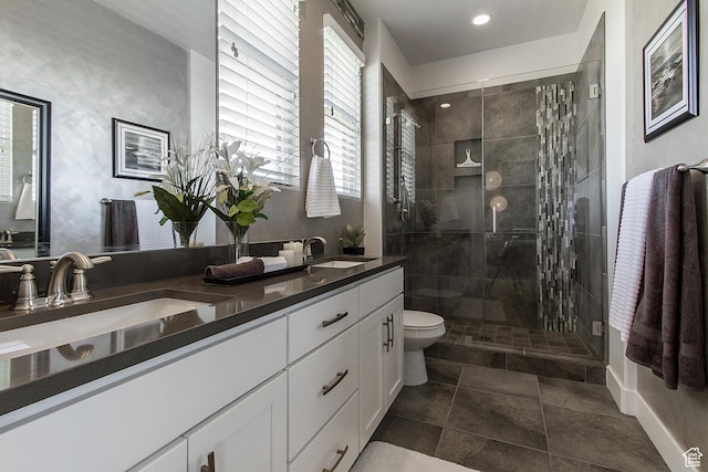 full bath with a sink, double vanity, toilet, and a stall shower