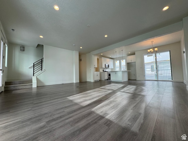 unfurnished living room with a chandelier, recessed lighting, and wood finished floors