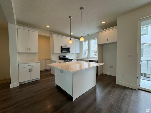 kitchen with recessed lighting, dark wood finished floors, white cabinetry, a kitchen island, and appliances with stainless steel finishes