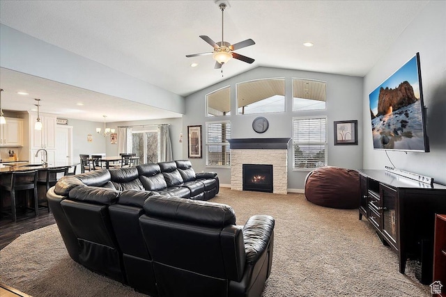 carpeted living room featuring plenty of natural light, ceiling fan with notable chandelier, lofted ceiling, and a fireplace