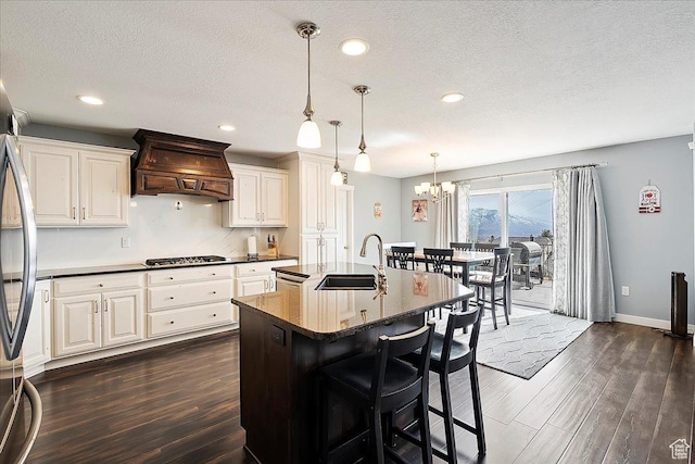 kitchen with custom exhaust hood, a breakfast bar area, a sink, dark wood finished floors, and stainless steel appliances