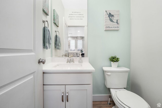 bathroom with toilet, baseboards, wood finished floors, and vanity