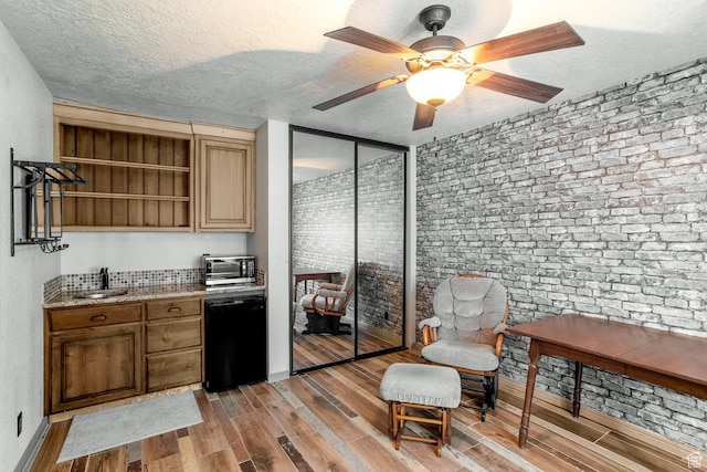 interior space featuring dishwasher, a textured ceiling, light wood-type flooring, and a sink