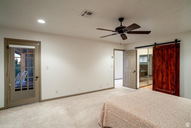 unfurnished bedroom featuring visible vents, a barn door, carpet flooring, access to outside, and baseboards
