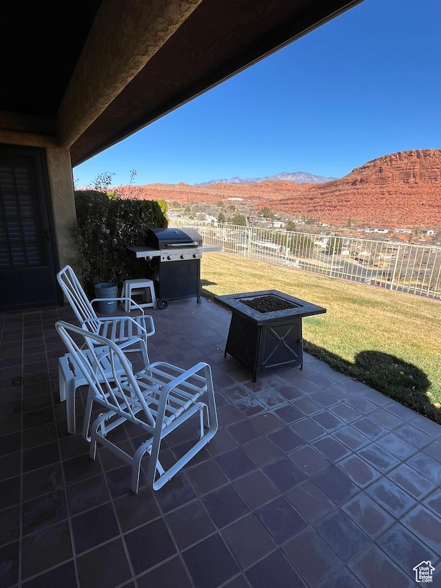 view of patio / terrace with a fire pit, area for grilling, fence, and a mountain view