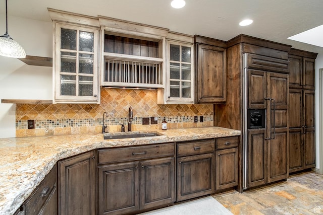 kitchen featuring paneled built in refrigerator, a sink, backsplash, open shelves, and stone finish floor
