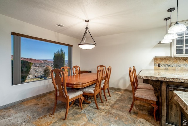dining space featuring stone finish flooring, visible vents, and baseboards