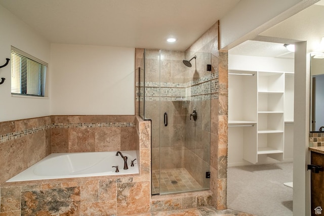 bathroom with a shower stall, a spacious closet, a bath, and vanity
