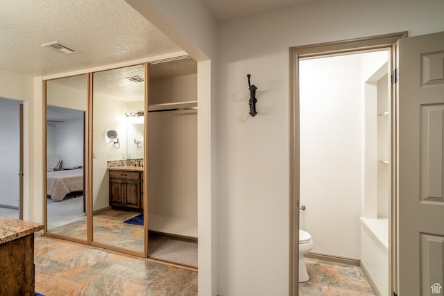 bathroom featuring visible vents, ensuite bathroom, stone finish flooring, a textured ceiling, and vanity