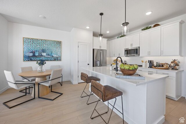 2893 S Malcom Pl Unit 9, West Valley City, UT 84128 - kitchen featuring stainless steel appliances, a kitchen breakfast bar, light wood finished floors, white cabinetry, and recessed lighting