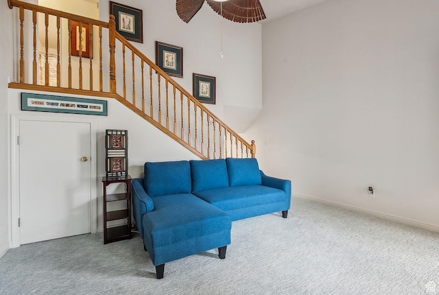 living room featuring a high ceiling, stairs, baseboards, and carpet flooring