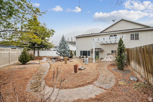 back of house with a fenced backyard and a pergola