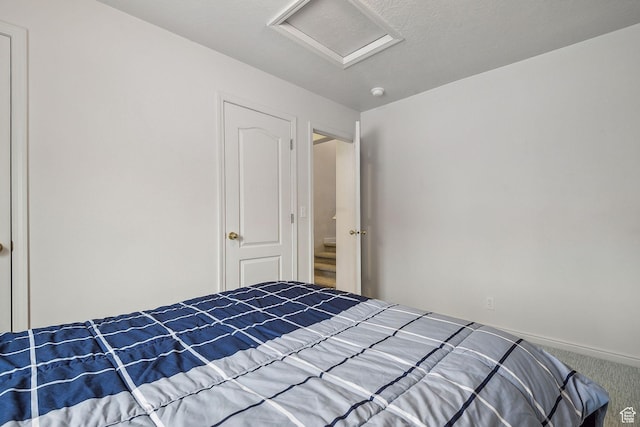 unfurnished bedroom with carpet floors, attic access, and baseboards