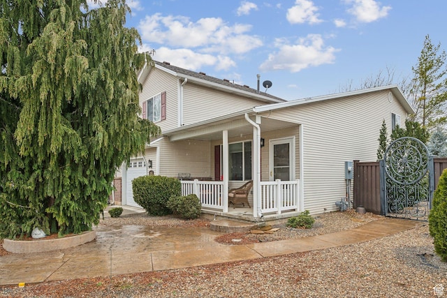 traditional home with a garage, fence, and a porch