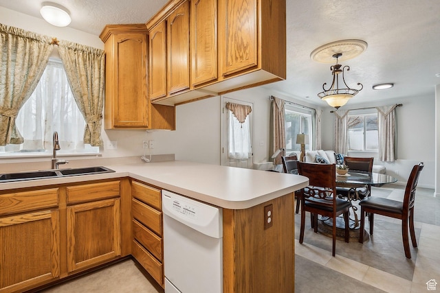 kitchen with dishwasher, light countertops, a sink, and brown cabinets