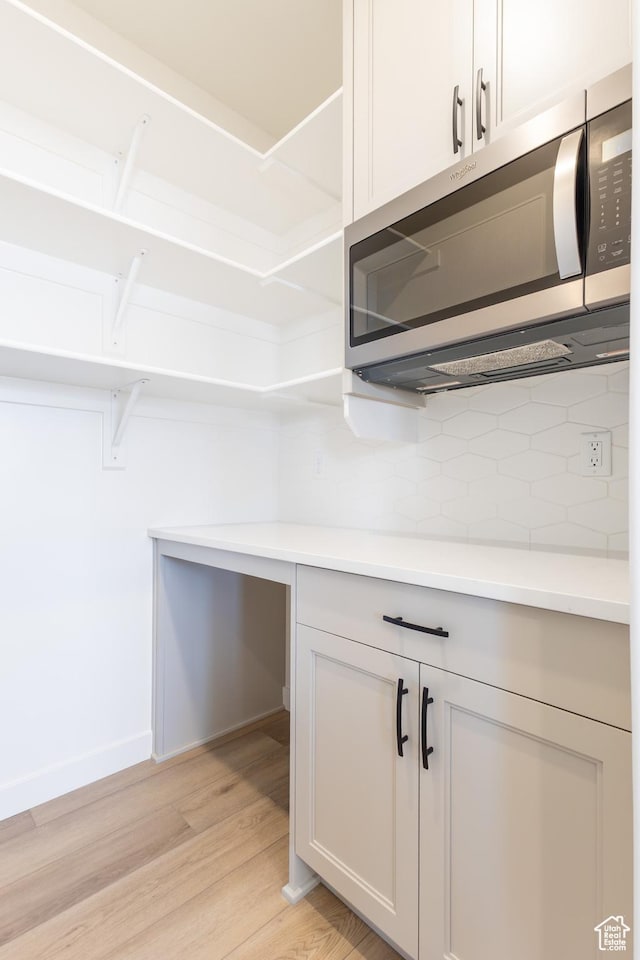 3062 N 2875 W Unit 24, Plain City, UT 84404 - detailed view of stainless steel microwave, decorative backsplash, light wood finished floors, and light countertops