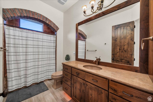 bathroom with toilet, curtained shower, wood finished floors, and vanity