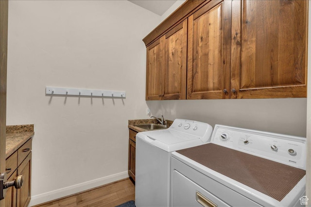 laundry room with cabinet space, baseboards, independent washer and dryer, light wood-style floors, and a sink