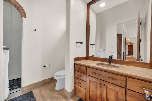full bath featuring toilet, walk in shower, wood finished floors, and vanity
