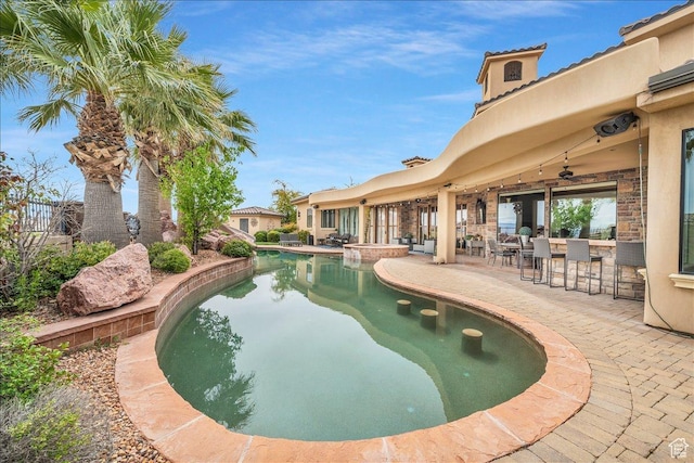 pool featuring outdoor dry bar, a patio area, and a ceiling fan
