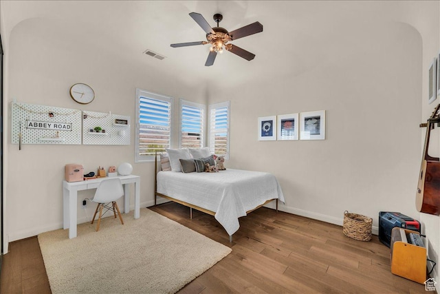 bedroom with ceiling fan, wood finished floors, visible vents, and baseboards