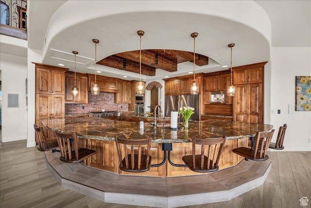 bar with baseboards, decorative backsplash, light wood-style flooring, stainless steel appliances, and a sink