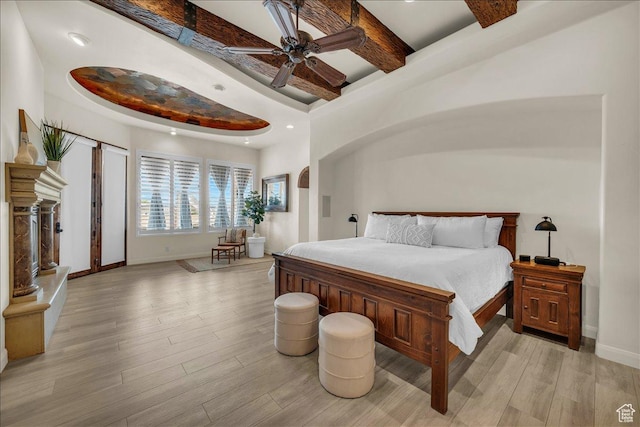 bedroom featuring a ceiling fan, beamed ceiling, light wood-style flooring, and baseboards