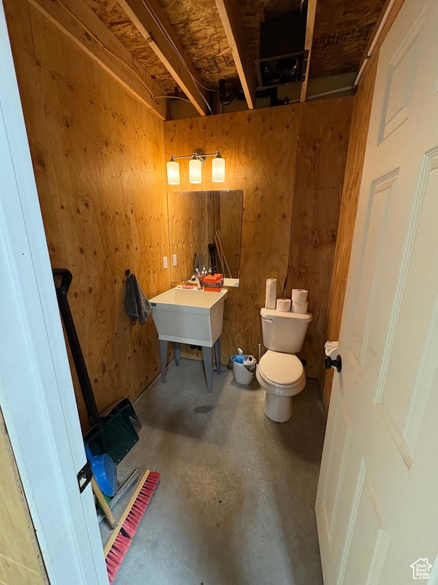 bathroom featuring unfinished concrete floors, toilet, and a sink