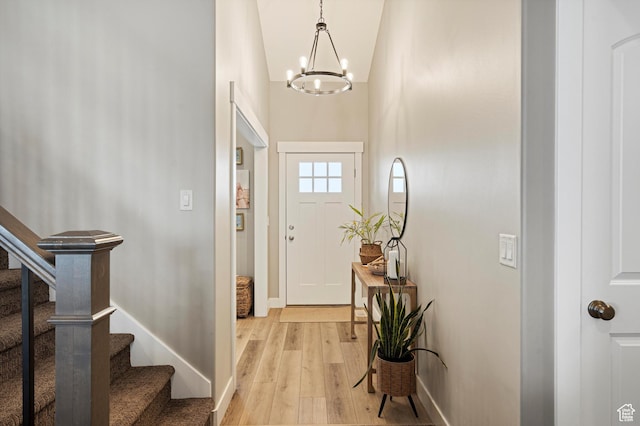 entryway with stairway, baseboards, light wood-type flooring, and a chandelier