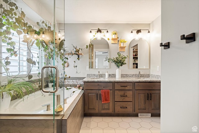 bathroom with a bath, visible vents, double vanity, and a sink
