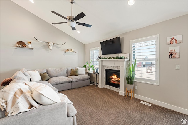 carpeted living room featuring visible vents, a glass covered fireplace, baseboards, lofted ceiling, and ceiling fan