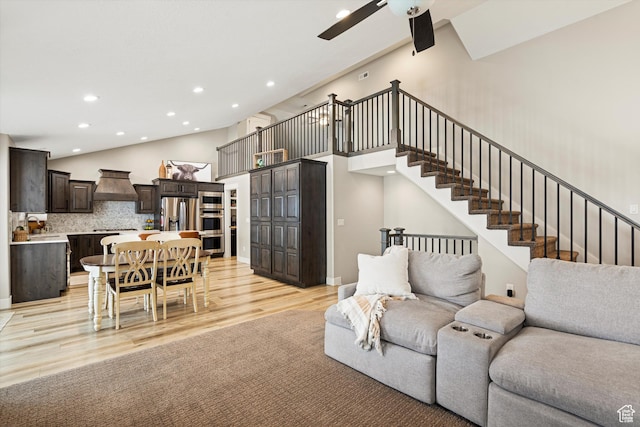 living area featuring light wood-type flooring, high vaulted ceiling, recessed lighting, ceiling fan, and stairs