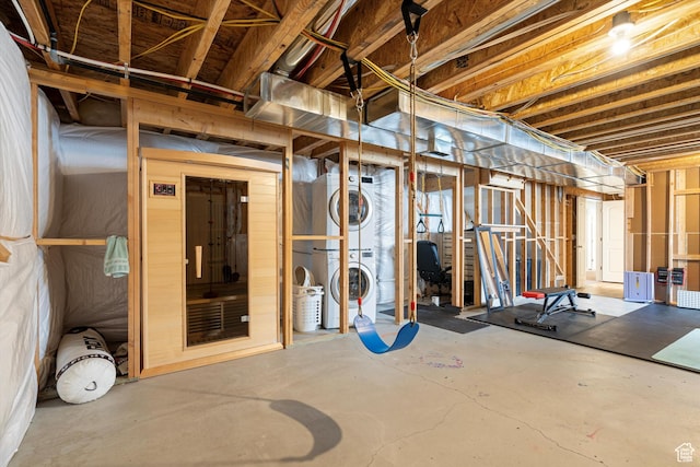 unfinished basement with stacked washer / drying machine