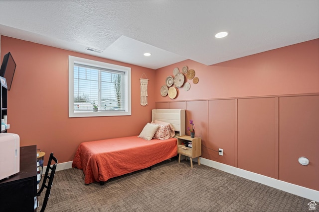 carpeted bedroom with visible vents, a textured ceiling, recessed lighting, wainscoting, and a decorative wall