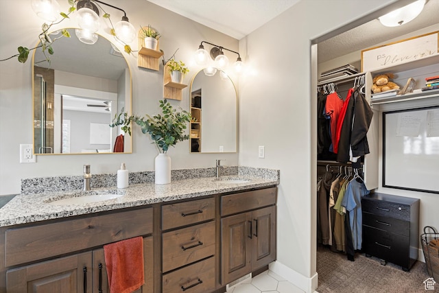 bathroom with a sink, a walk in closet, baseboards, and double vanity