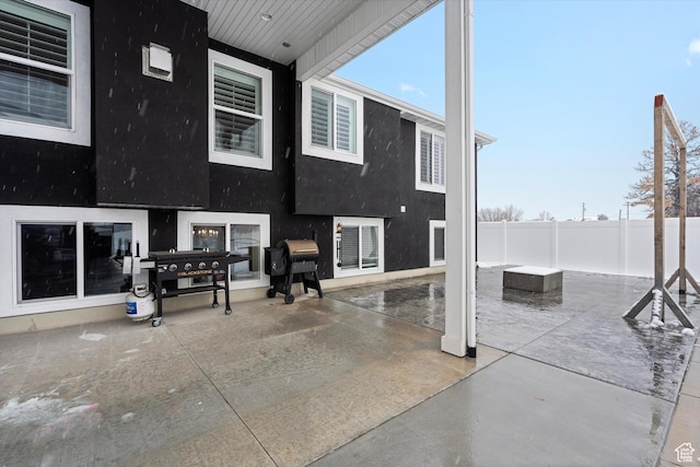 rear view of house with stucco siding, a patio, and fence